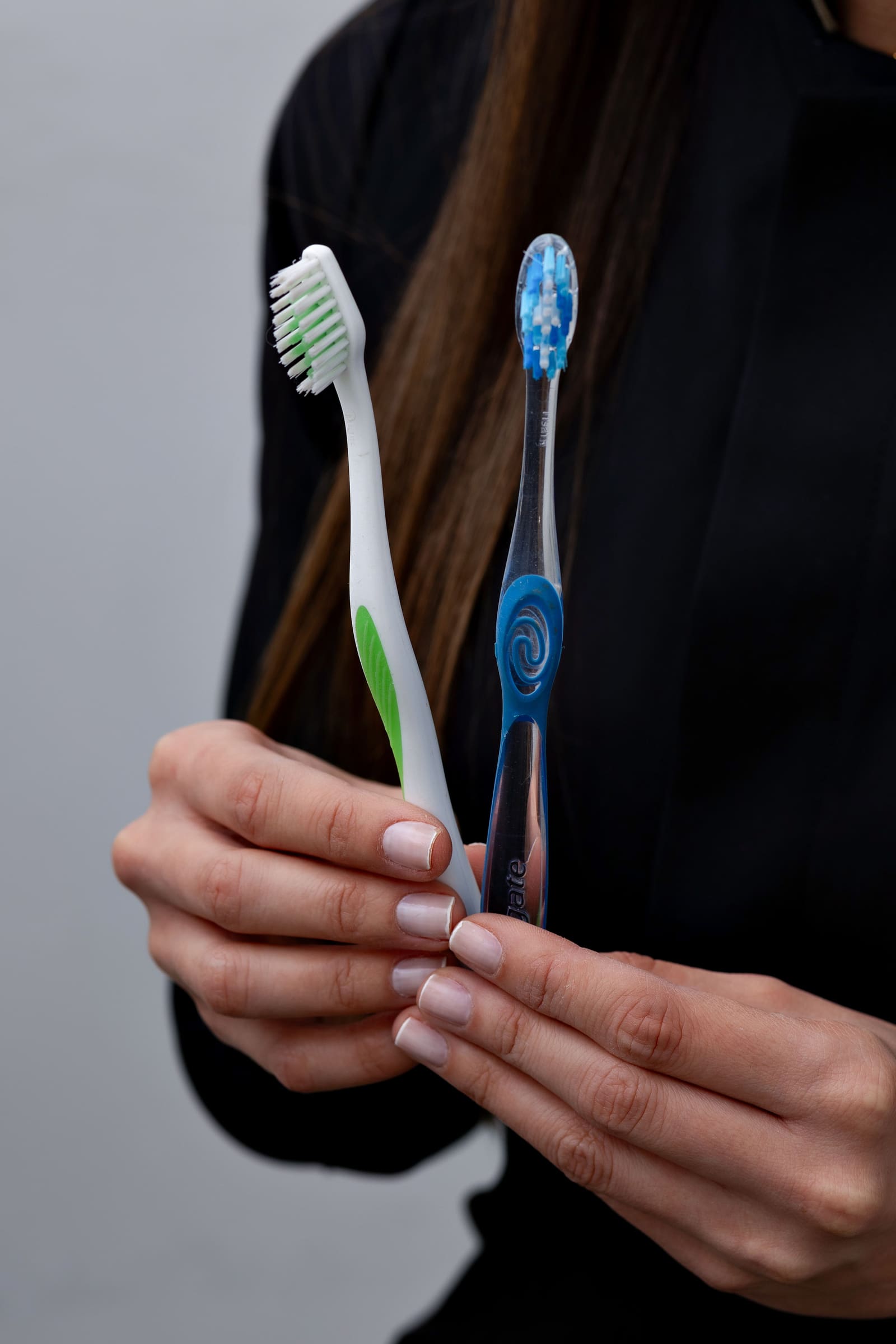 Duas escovas de dente seguradas nas mãos, representando higiene bucal