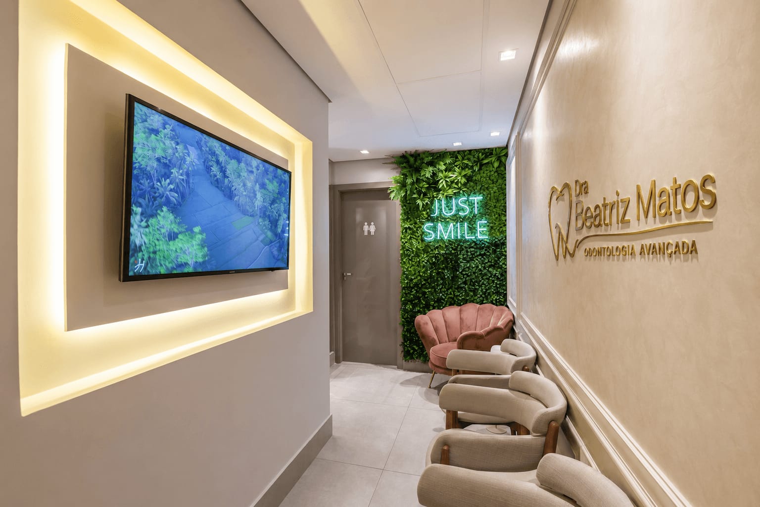 Corredor da recepção com parede de plantas e letreiro Just Smile na clínica em Sorocaba